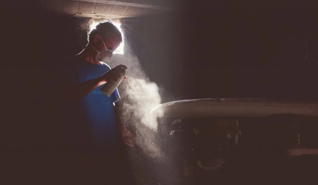 man spraying on surfboard