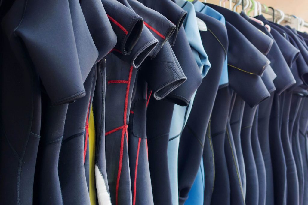 Line of multiple hanging wetsuits 