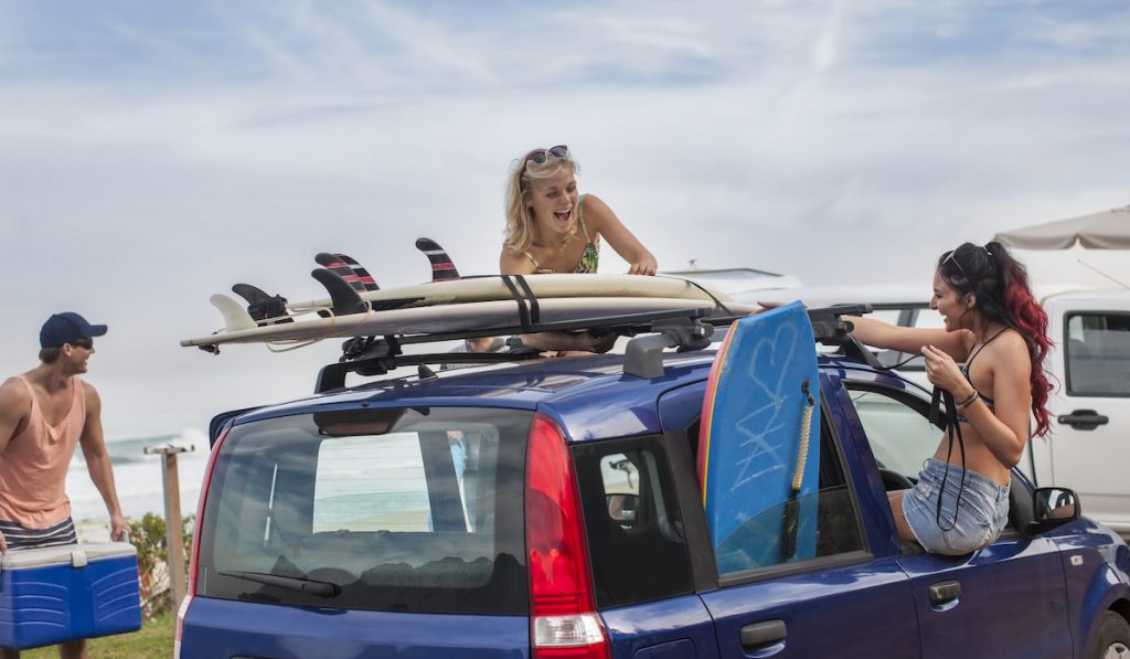 friends with surfboards on top of a their car