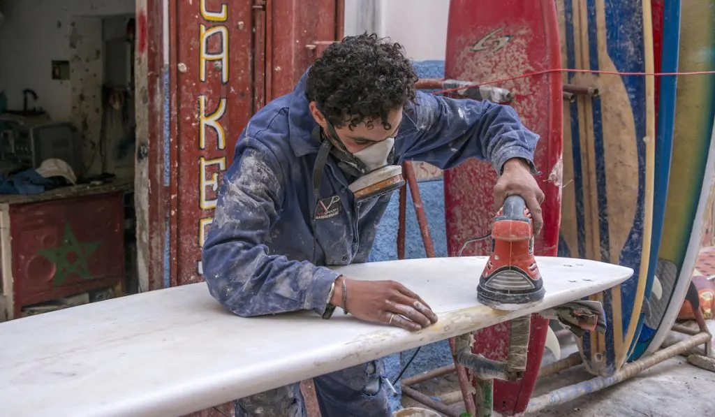 worker polishing surfboard