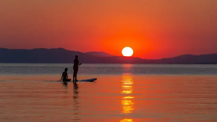 two young girls on a paddleboard during sunset