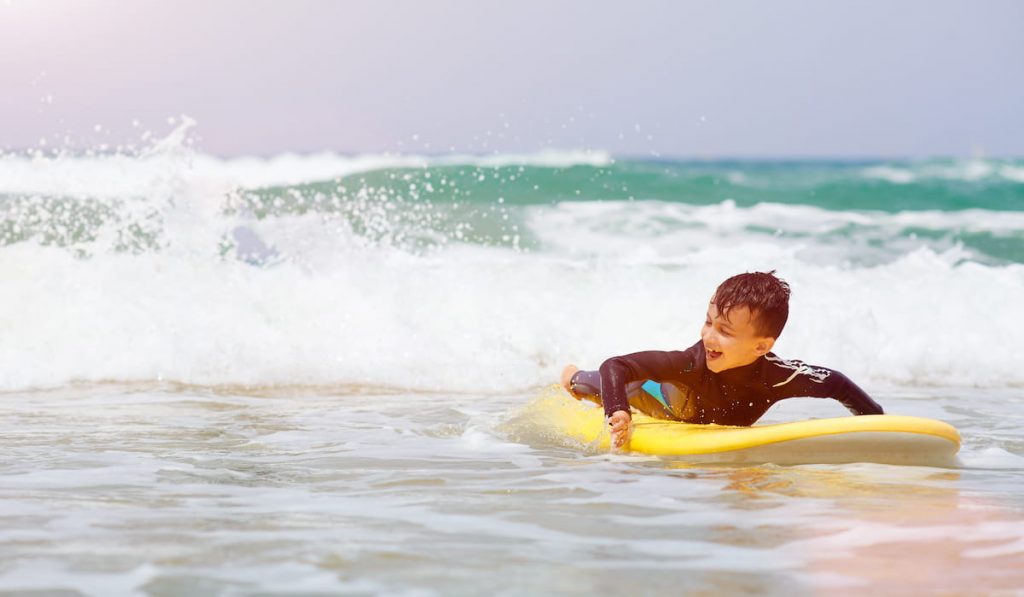 A young surfer is looking at the ocean