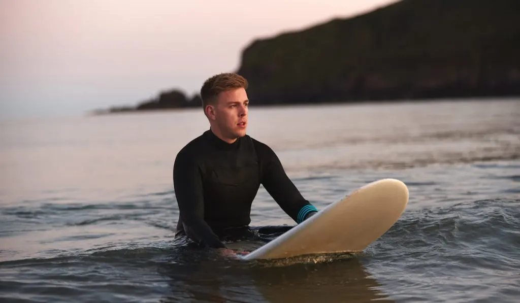 Man Sitting And Floating On Surfboard On Calm Sea 