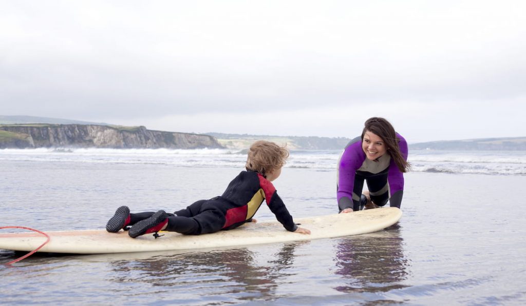 Mother teaching son how to surf