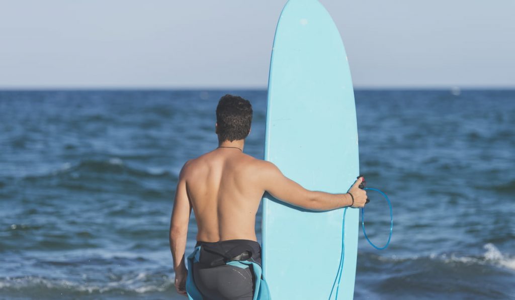 Surfer holding his blue surfboard