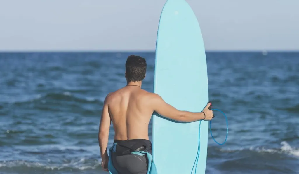 Surfer holding his blue surfboard