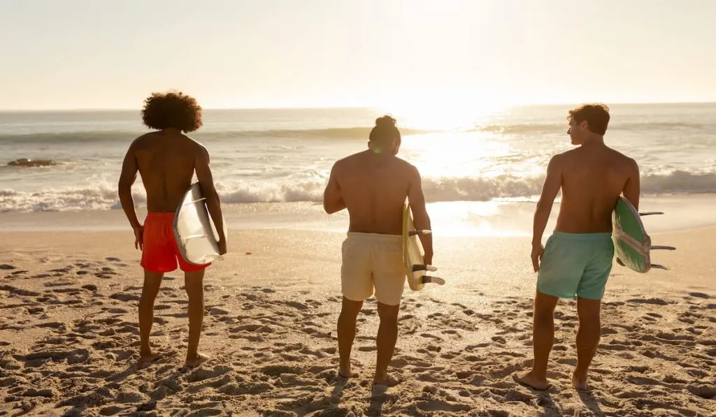 Young mixed race men holding surf boards on beach