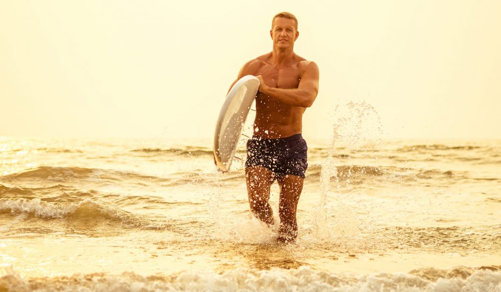 man is standing with a surf in his hands on the sea shore