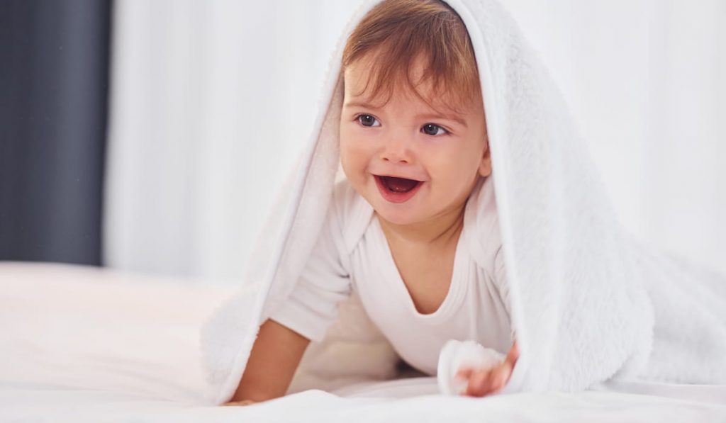 smiling baby with a white towel on his head