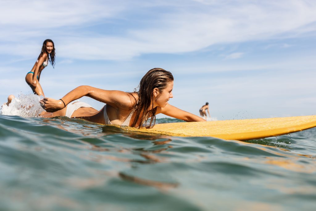 two-beautiful-sporty-girls-surfing-in-the-ocean