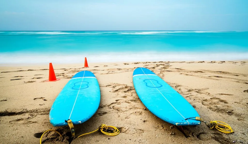 two blue surfboards on a sandy beach