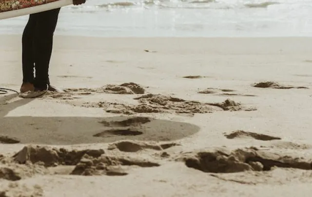 Surfer carrying a surfboard at the beach - ee220815