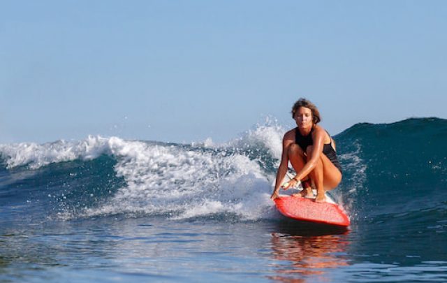 young female surfer riding wave on surfboard - ee220803