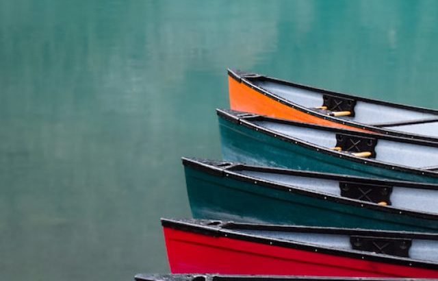 Colorful canoe lined up on turquoise water lake - ee220913