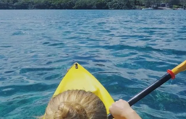 View from behind woman kayaking in the tropical setting - ee220913