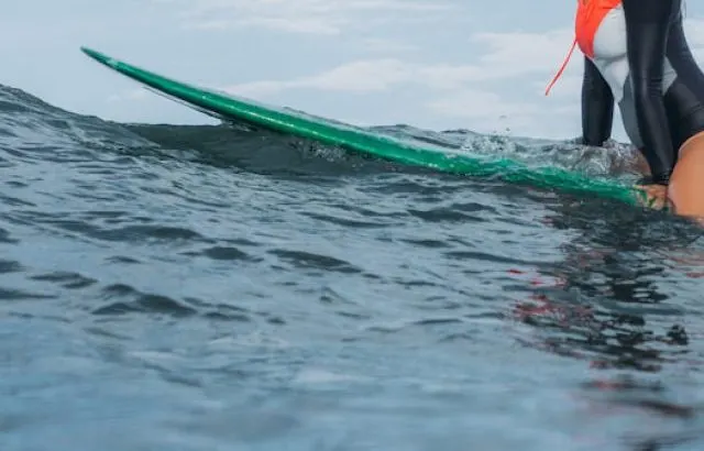 female surfer sitting on surf board in ocean - ee220924