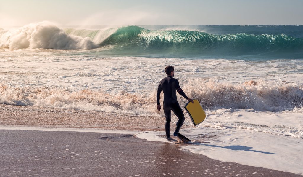 surfer by shore with awesome beach wave breaks in front