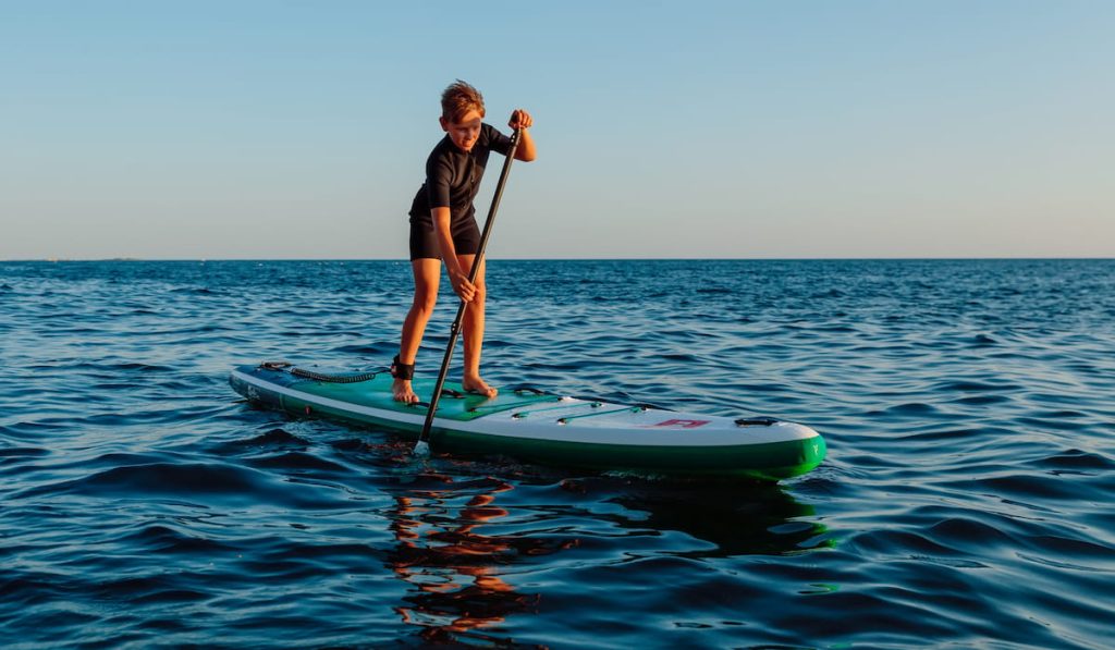 Young boy on stand up paddle board at ocean 