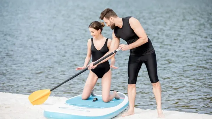 teaching young woman to surf on the standup paddleboard
