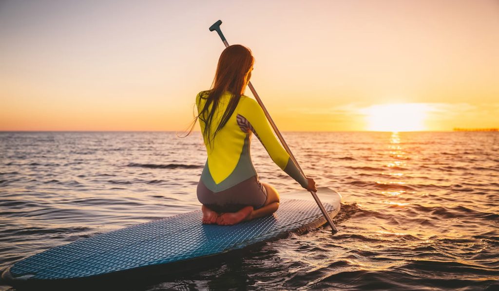 woman on stand up paddle board enjoying the sunset view