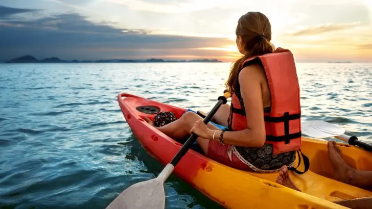 woman wearing life vest manouver kayak