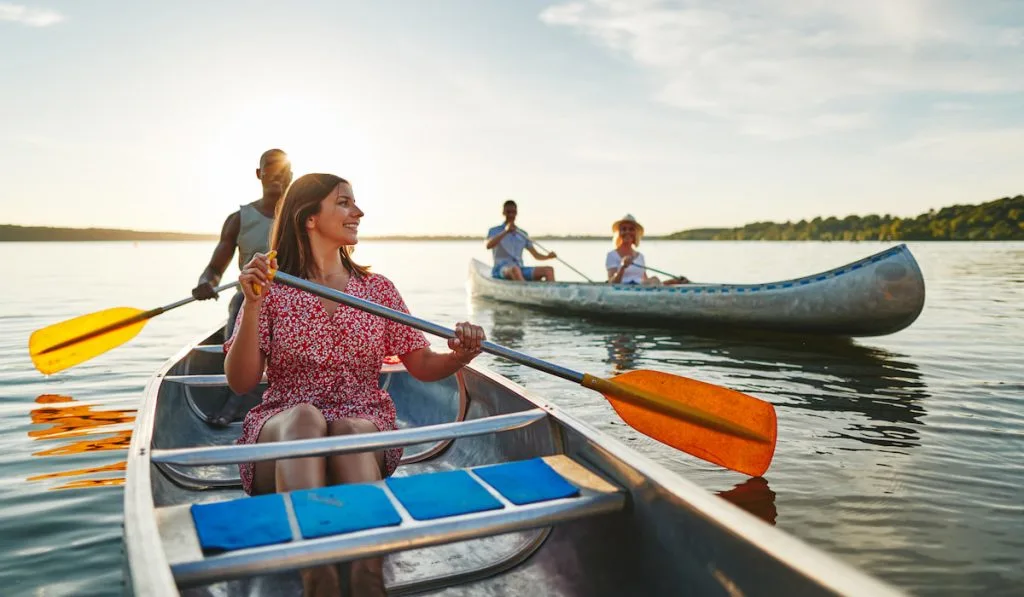 Happy couple canoeing with another couple on a lake