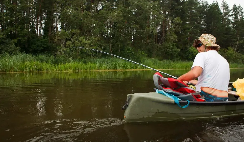 Man fishing in river from canoe