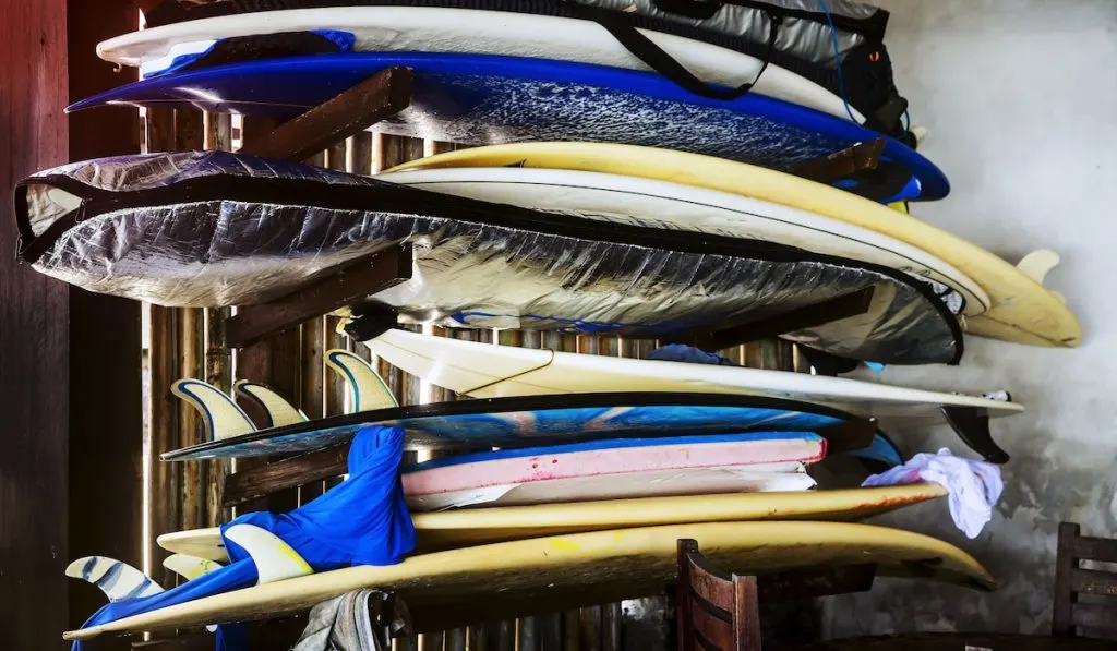 stack of surfboards, other are stored in a surfboard bag