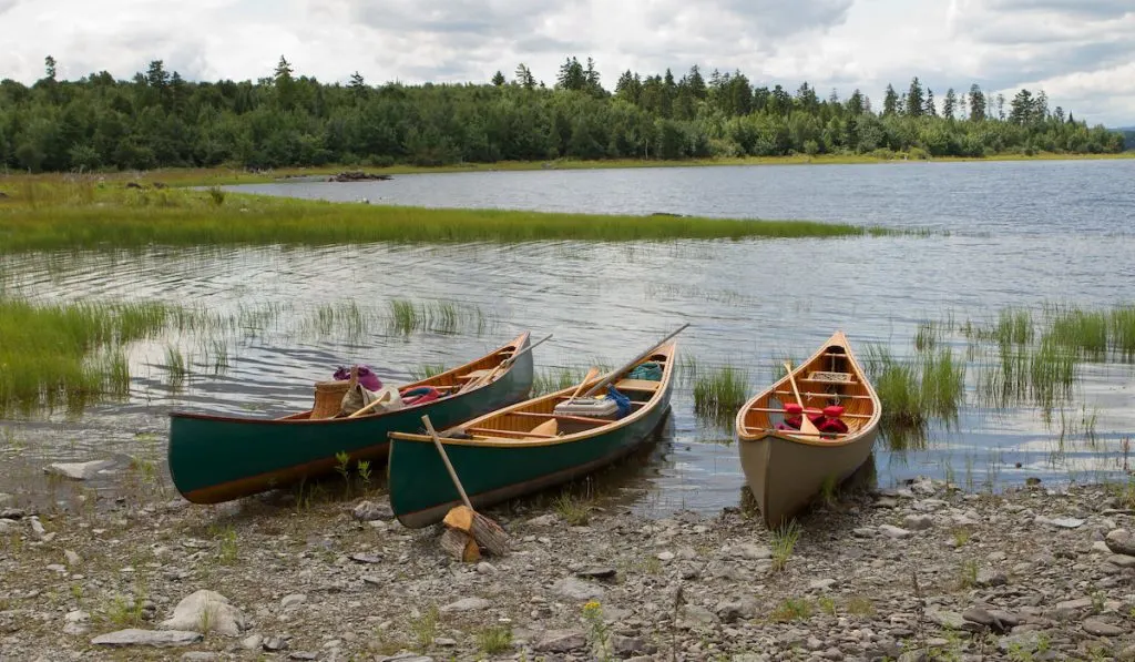 Three canoes on a lake rocky beach in the Maine wilderness