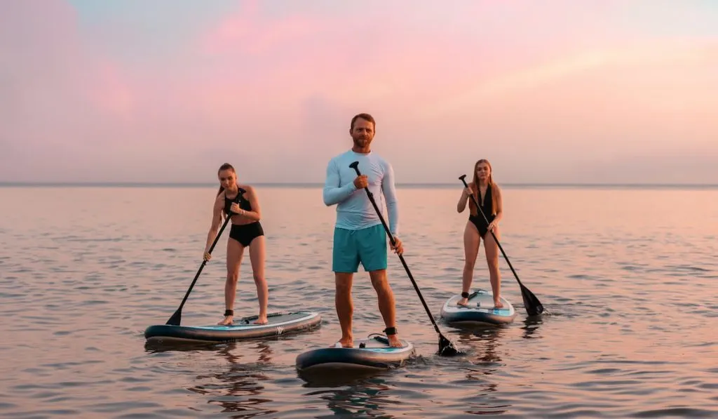 friends stand up paddling on a sup boards at the ocean