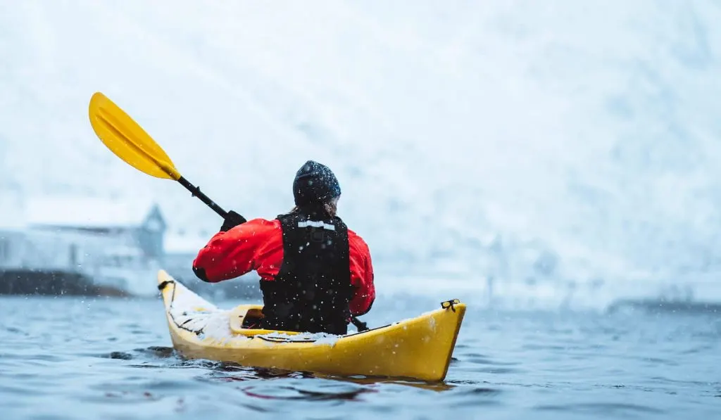 woman paddling a kayak at winter season 