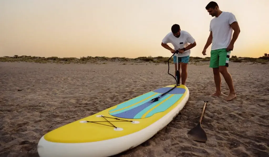 Young man inflating paddle sup board 