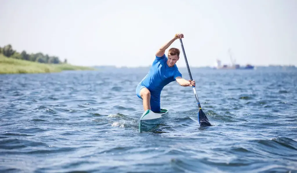 young man rowing in canoe along a river 