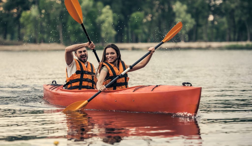 couple in sea vests is smiling while sailing a kayak 