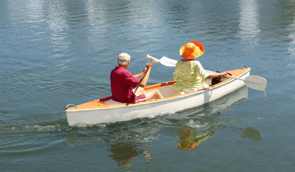 old couple rowing canoe on lake