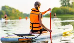 woman wearing life jacket sitting on a paddleboard