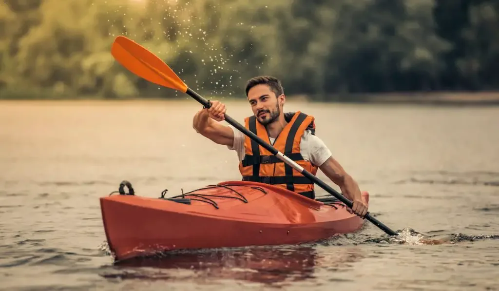 young man in life vest sailing a kayak