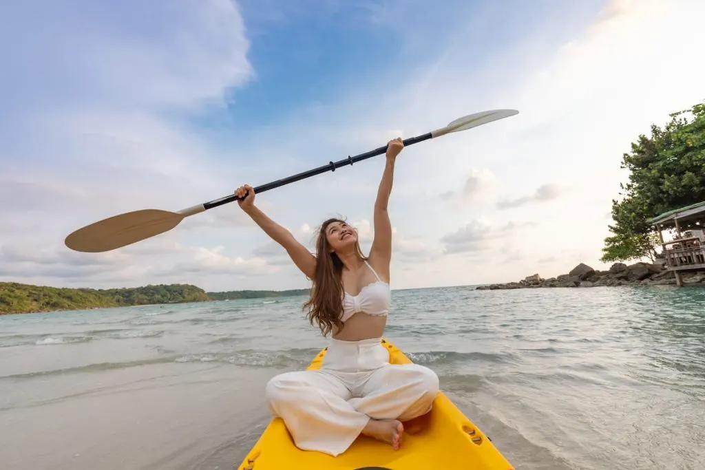 young woman wearing baggy jeans, enjoy kayaking 